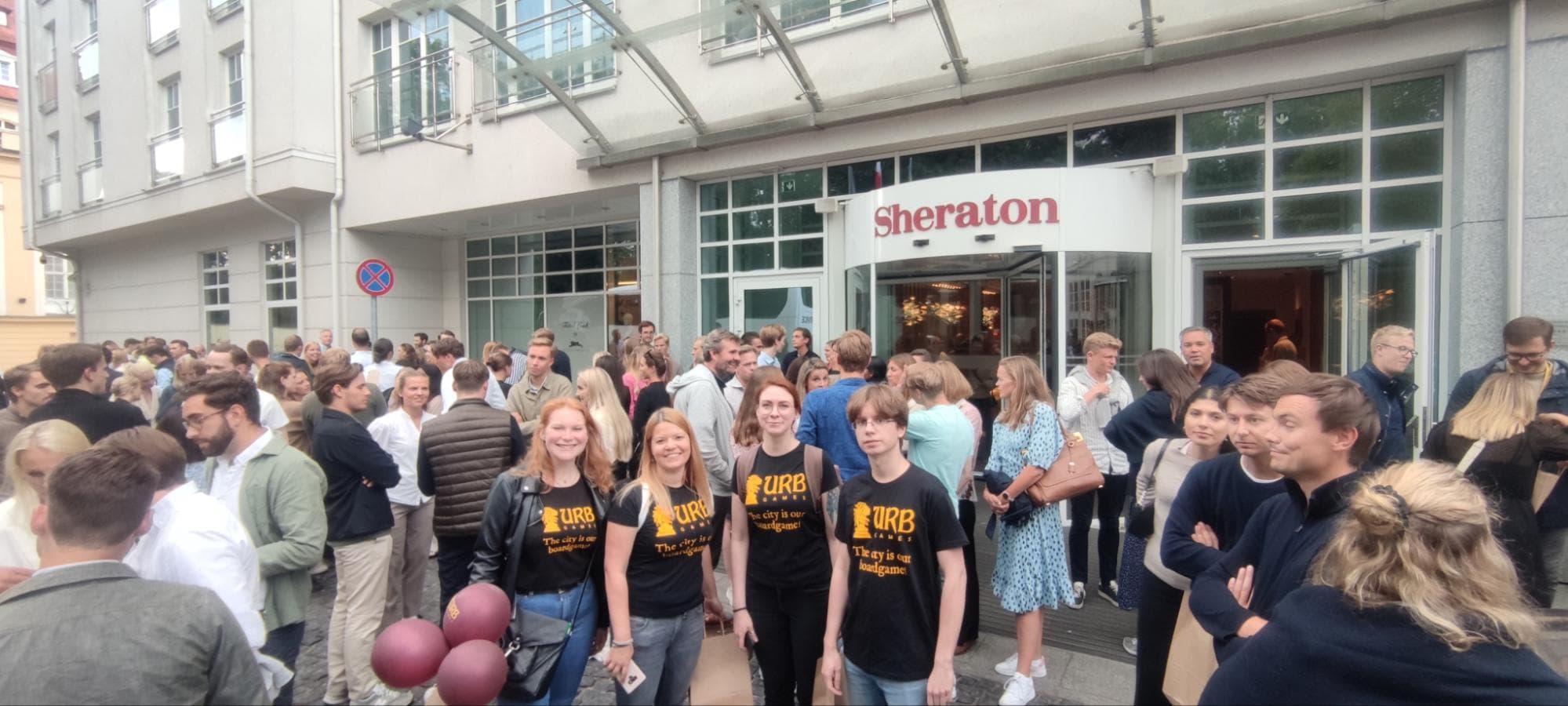 Duża grupa uczestników gry miejskiej UrbGames przed hotelem